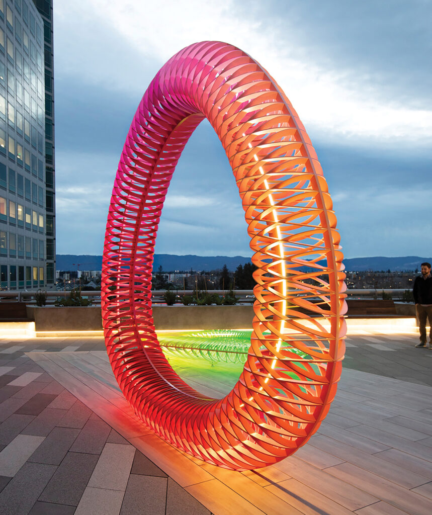 a glowing orange and pink ombre spiral sculpture at dusk