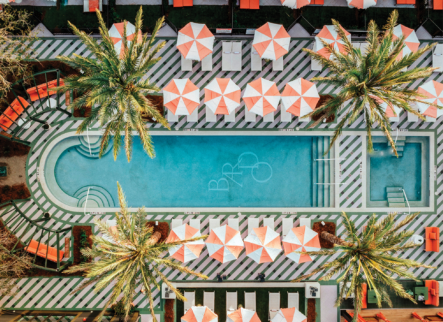 an aerial view of a pool and palm trees