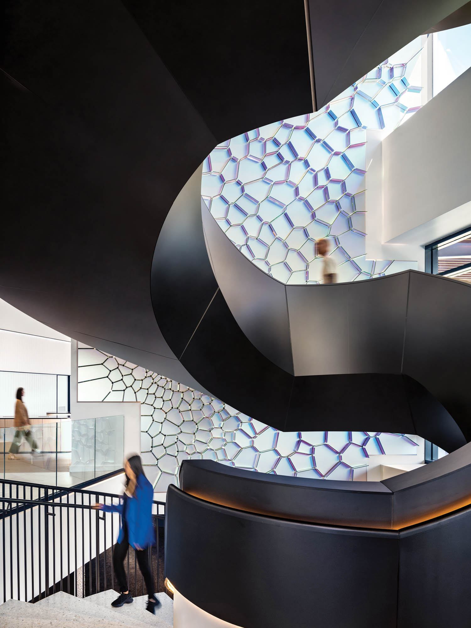 woman standing below black winding staircase