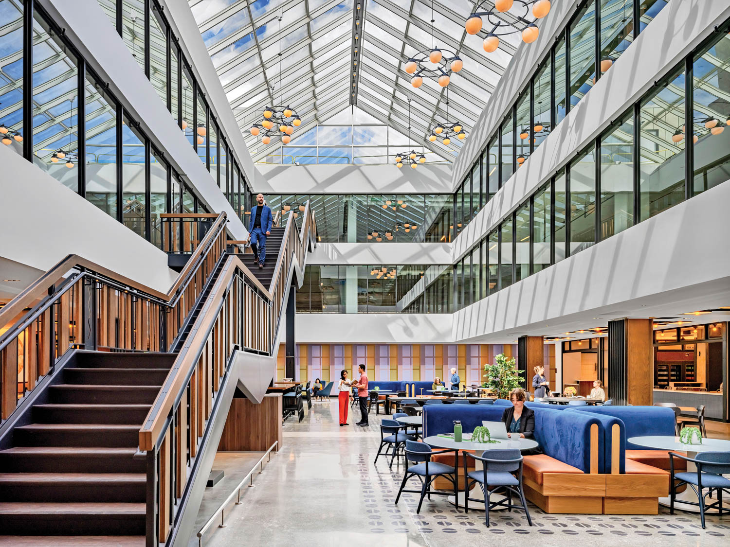 sitting area with long staircase, blue seating and enclosed hallways by Elkus Manfredi Architects