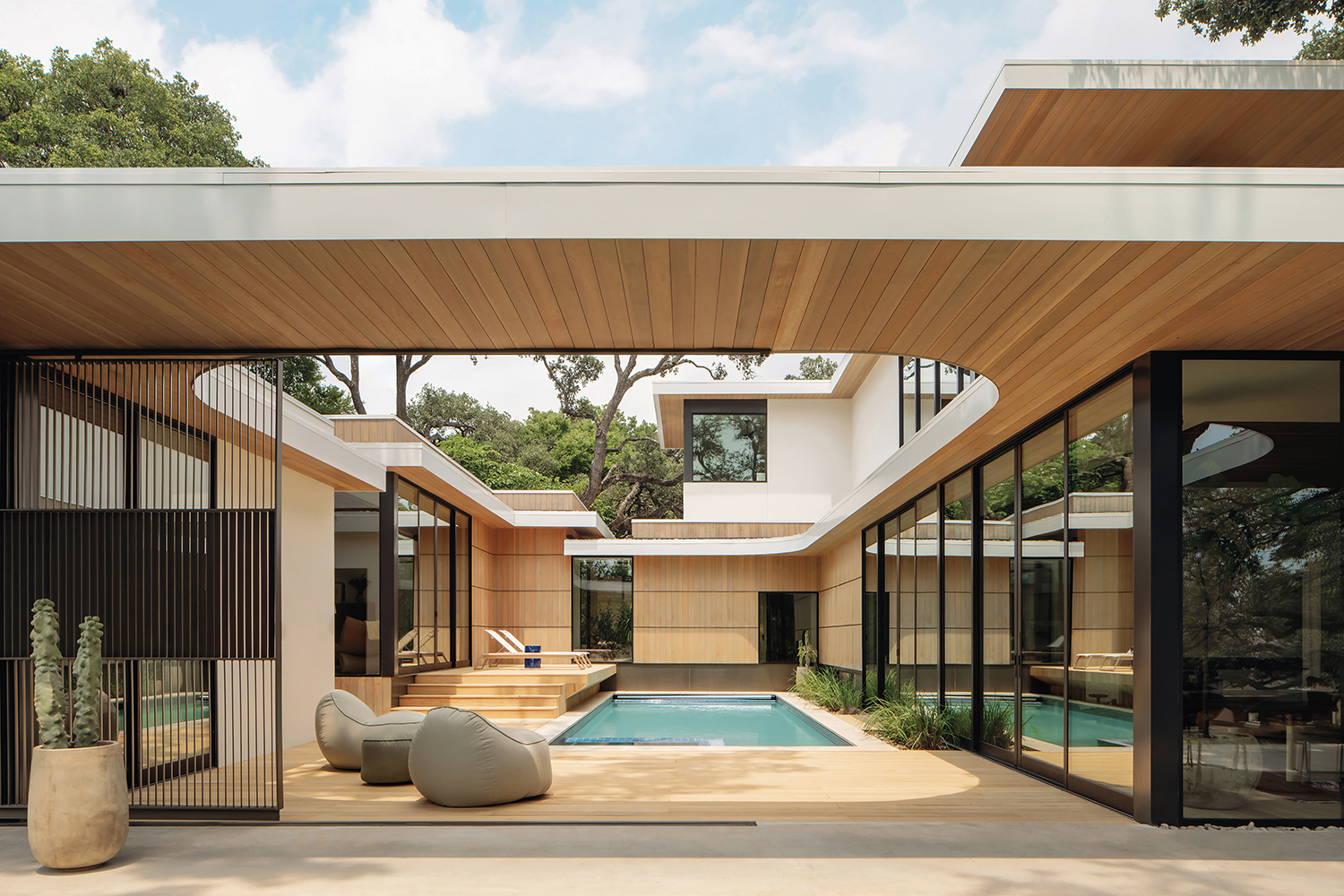 indoor-outdoor living area of an Austin home with light wood finishes around a pool