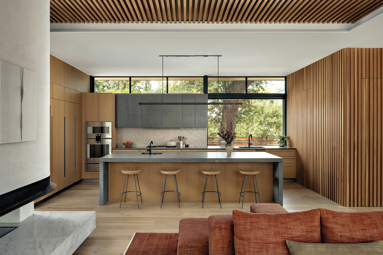 contemporary kitchen with a gray stone island and a slatted hemlock wall on one side