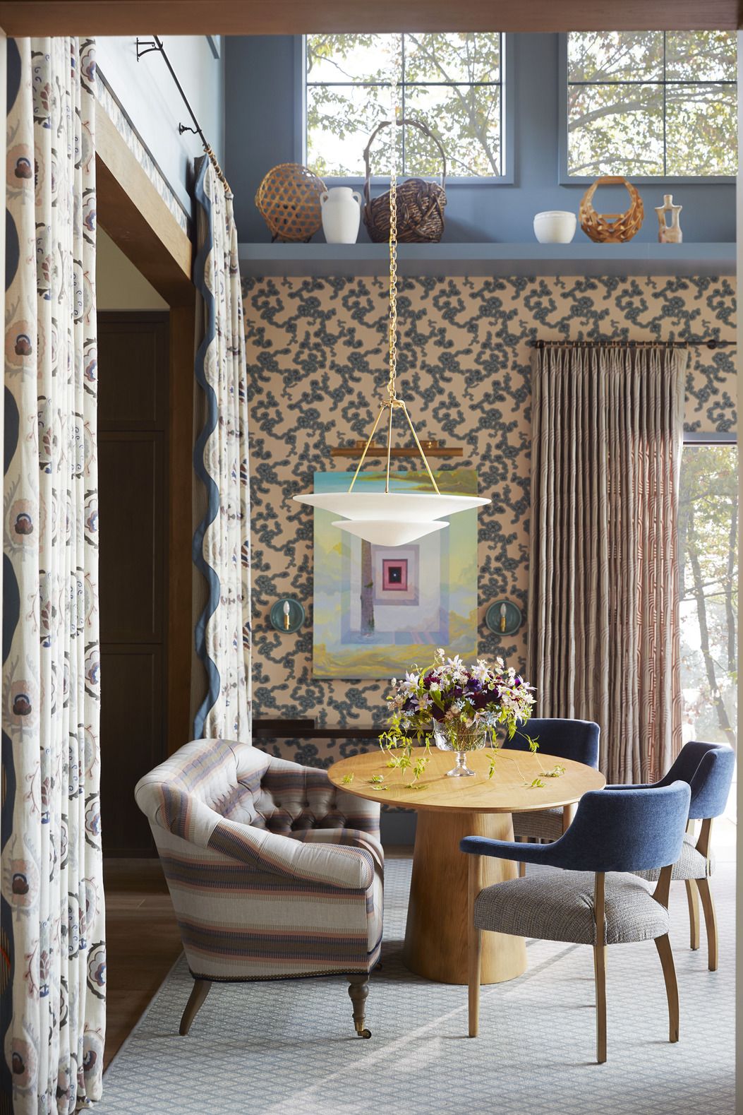 the living dining room: by dane austin design daneaustindesign. floor to ceiling chimney breast, constructed with cosentino dekton ultracompact surface material. a farrow ball cherry blossom–inspired wallpaper (reproduced from a design discovered in an 18th century château) is a stunning backdrop. blue walls. dining area a plaster finished visual comfort co. pendant hangs low over the table. table: wayfair professional. drapery fabric: sanderson.whole home 2024. this year energy efficient home is in the conservation minded community of sprout, located on a private nature preserve in hendersonville, north carolina. living room, dining room.