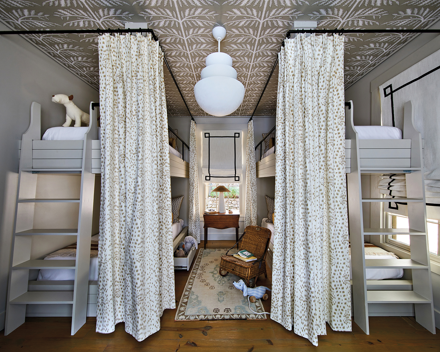 bunk beds surrounded by tall drapes under a vine-patterned ceiling
