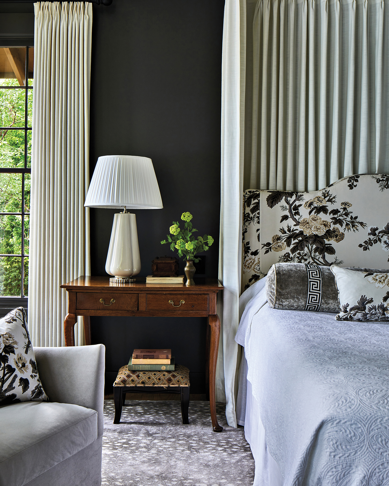 traditional bedroom with dark walls, floral bed frame and a vintage side table