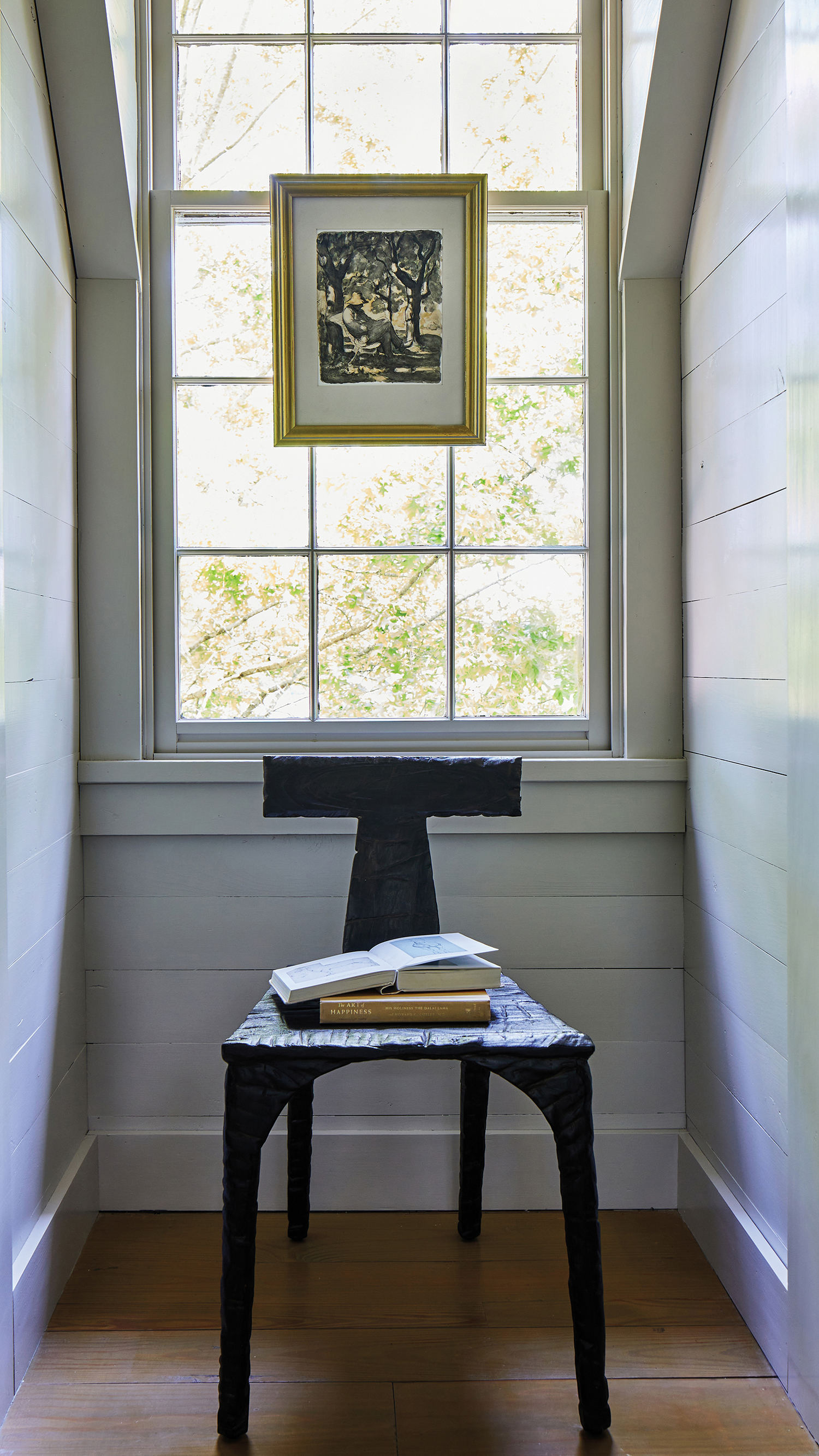 landing with a sculptural chair and a painting atop the window